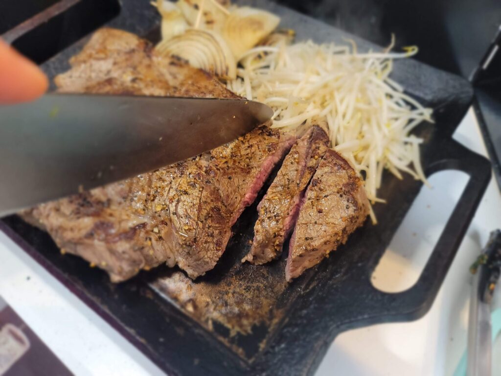 鉄板で焼いた肉をカットしている